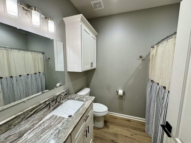 full bath featuring visible vents, toilet, wood finished floors, baseboards, and vanity