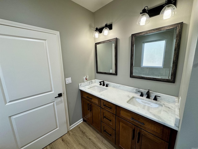 bathroom with a sink, baseboards, wood finished floors, and double vanity