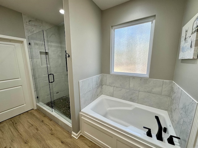 full bath with a stall shower, a garden tub, and wood finished floors