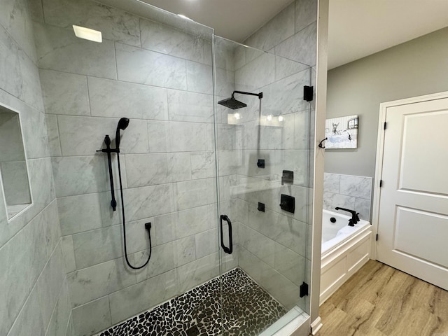 full bathroom featuring wood finished floors, a shower stall, and a bath