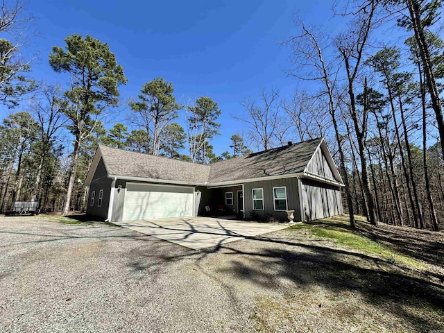 view of front of property featuring an attached garage, driveway, and roof with shingles