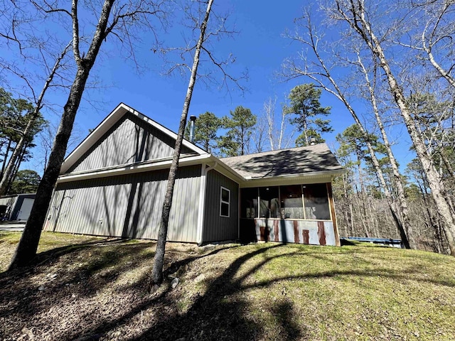 exterior space with a yard, a sunroom, and roof with shingles