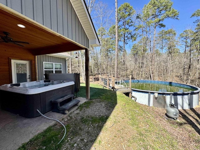 view of yard featuring ceiling fan, an outdoor pool, central AC, and a hot tub