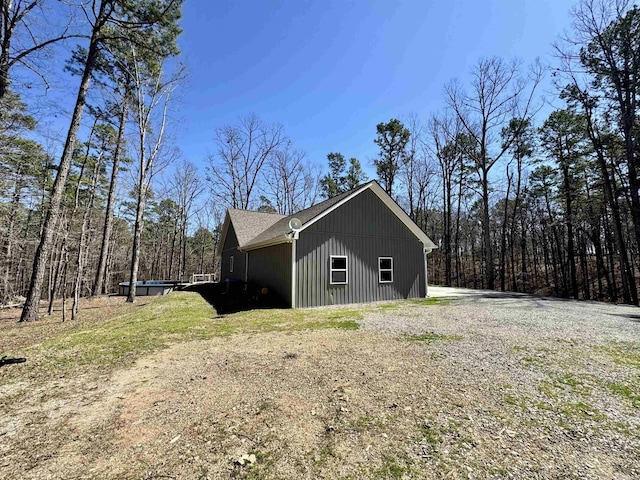 view of side of property featuring driveway and a shingled roof