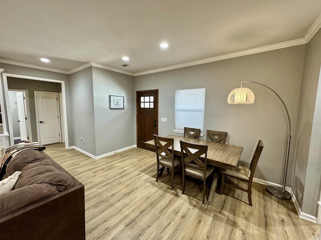 dining area with baseboards, crown molding, and light wood finished floors