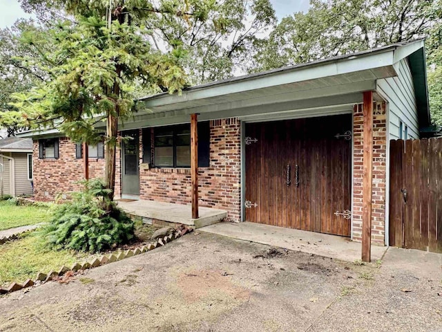 view of front of property featuring covered porch, a garage, fence, and brick siding