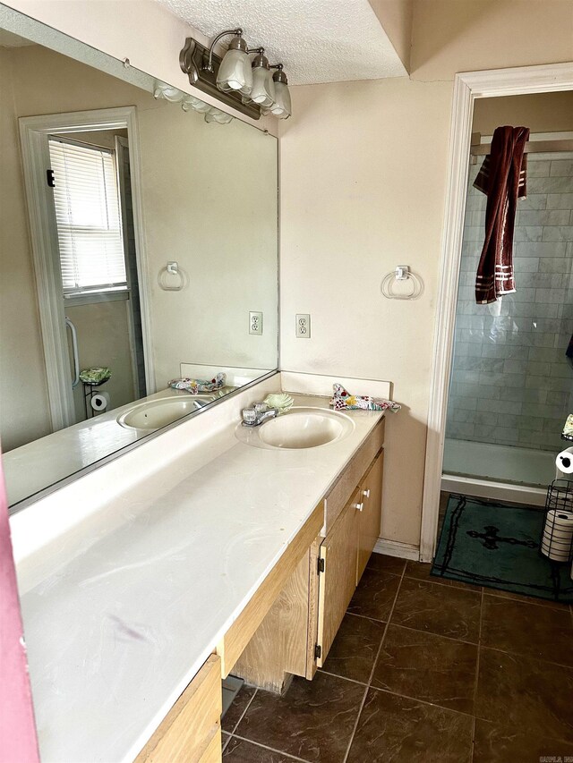 full bath with tile patterned flooring, a shower stall, a textured ceiling, and vanity