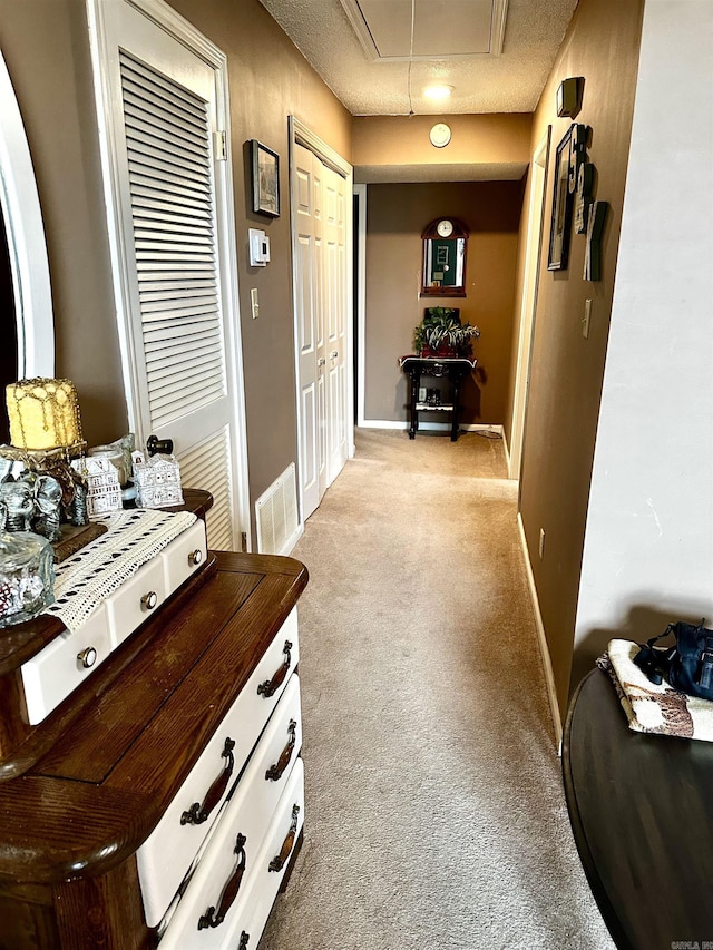 corridor featuring visible vents, light colored carpet, attic access, and baseboards