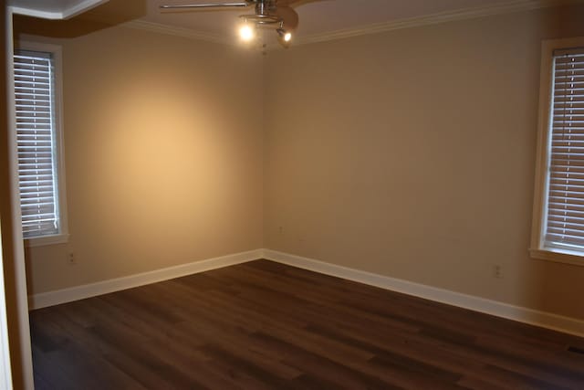 unfurnished room with crown molding, baseboards, and dark wood-style flooring