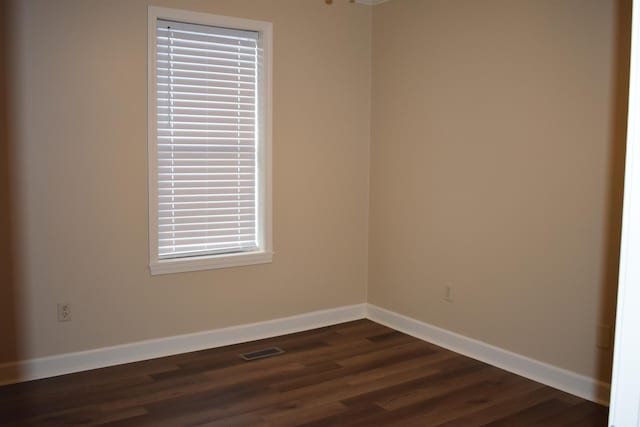 spare room with visible vents, baseboards, and dark wood-style floors