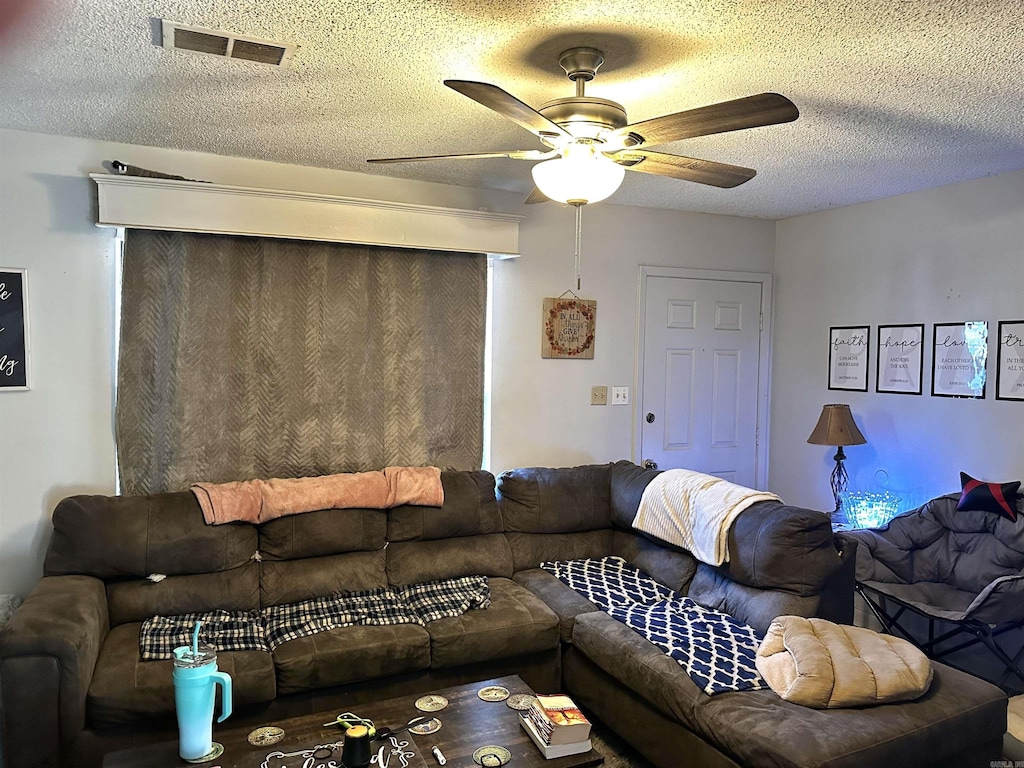 living area with visible vents, a textured ceiling, and ceiling fan