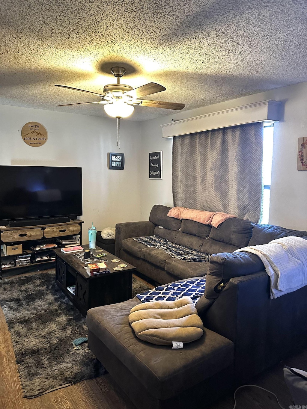 living area featuring a textured ceiling, wood finished floors, and a ceiling fan