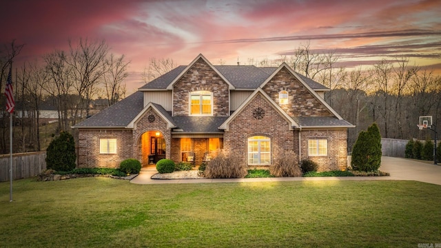 craftsman-style home featuring brick siding, roof with shingles, a front lawn, and fence