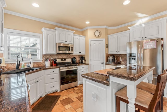 kitchen with white cabinetry, a kitchen breakfast bar, appliances with stainless steel finishes, and a sink