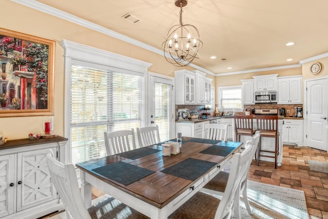 dining space with crown molding, stone finish floor, visible vents, and a chandelier