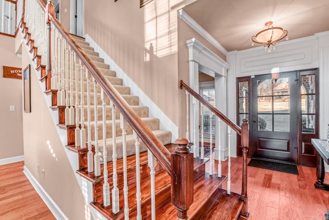 foyer entrance featuring baseboards, wood finished floors, and crown molding