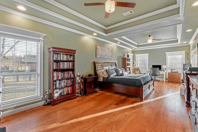 bedroom featuring hardwood / wood-style floors, a tray ceiling, visible vents, and ornamental molding