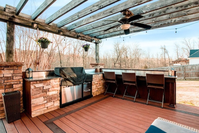 wooden deck featuring fence, an outdoor kitchen, outdoor wet bar, area for grilling, and ceiling fan