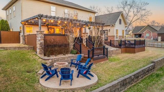 back of property at dusk with fence, a pergola, a fire pit, a patio area, and a lawn