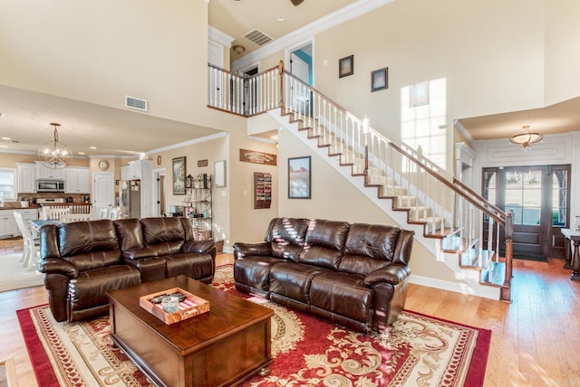 living room featuring wood finished floors, visible vents, baseboards, stairs, and crown molding