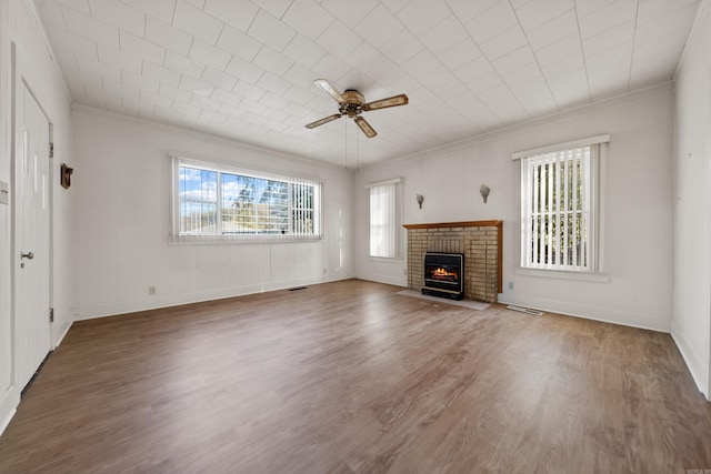 unfurnished living room featuring a brick fireplace, wood finished floors, a ceiling fan, and ornamental molding