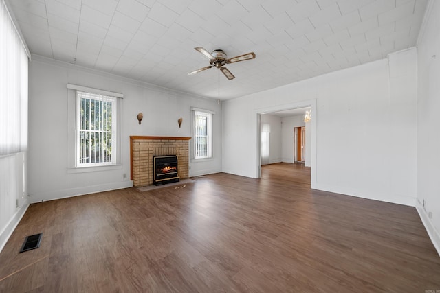 unfurnished living room featuring a wealth of natural light, visible vents, a brick fireplace, and wood finished floors