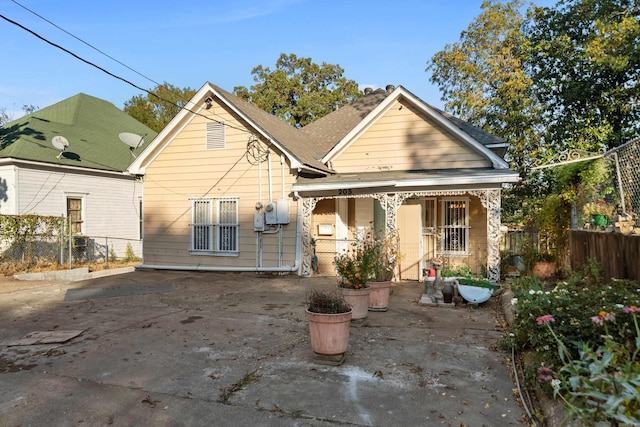 rear view of property featuring a porch and fence