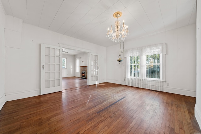 interior space featuring plenty of natural light, a fireplace, an inviting chandelier, and hardwood / wood-style floors