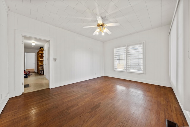 empty room featuring baseboards, dark wood-style floors, visible vents, and ceiling fan