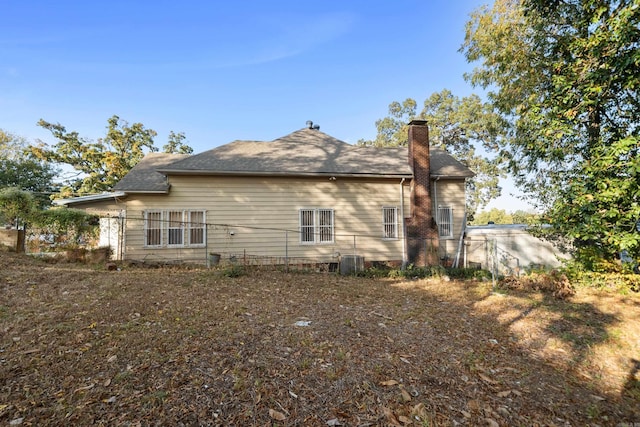 back of property featuring central AC unit and a chimney