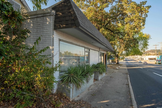 view of side of home featuring mansard roof and a shingled roof