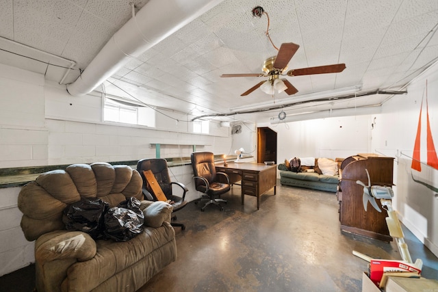 below grade area with ceiling fan and concrete block wall