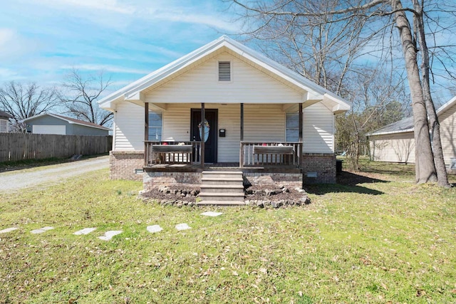 bungalow-style home with brick siding, a porch, a front lawn, and fence