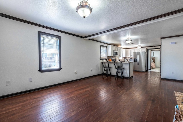 kitchen with a peninsula, white cabinets, appliances with stainless steel finishes, and ornamental molding