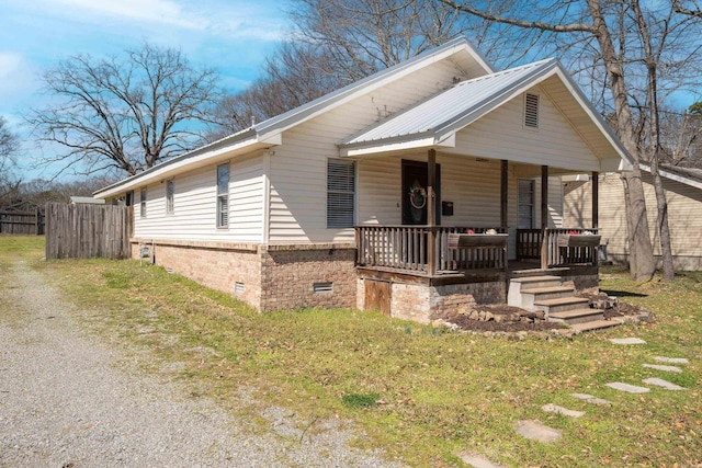 view of front of home with a porch, fence, metal roof, crawl space, and brick siding