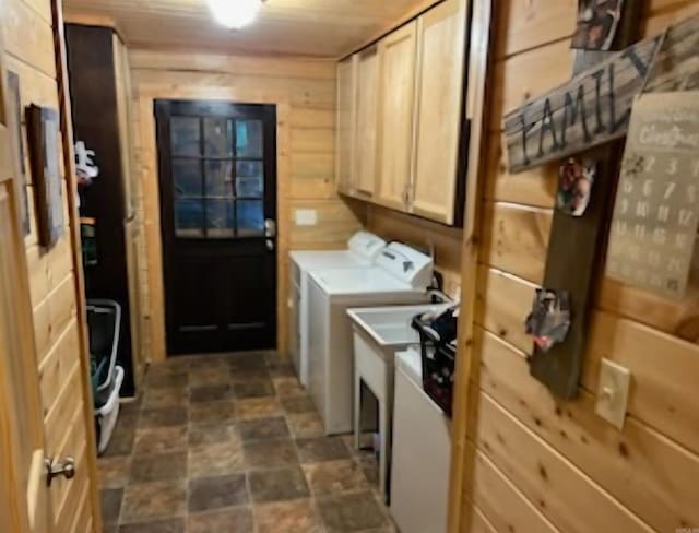 washroom featuring cabinet space, washer and dryer, stone finish flooring, and wood walls