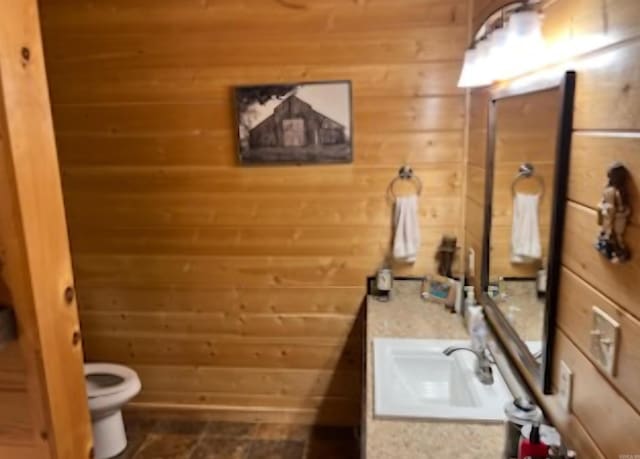 bathroom with wooden walls, toilet, and vanity