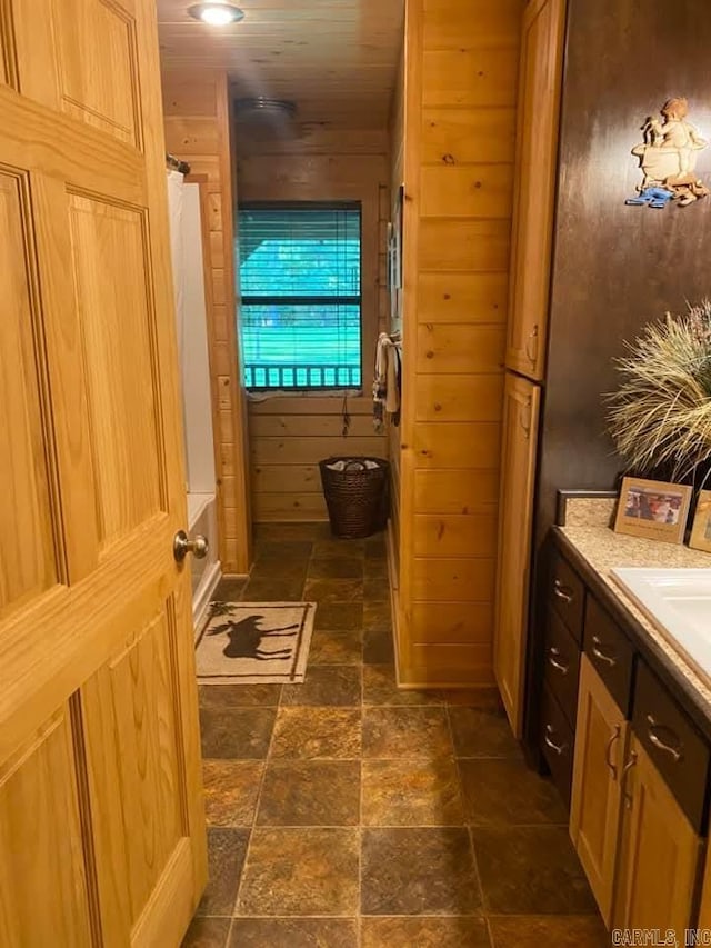 bathroom featuring wood walls, curtained shower, vanity, and stone finish floor