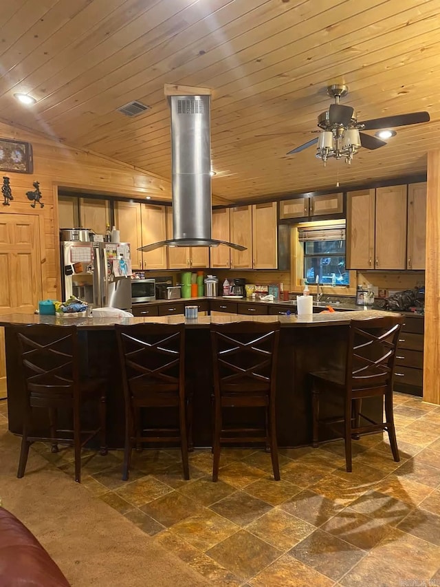 kitchen featuring a ceiling fan, stainless steel appliances, wood ceiling, a kitchen breakfast bar, and island range hood