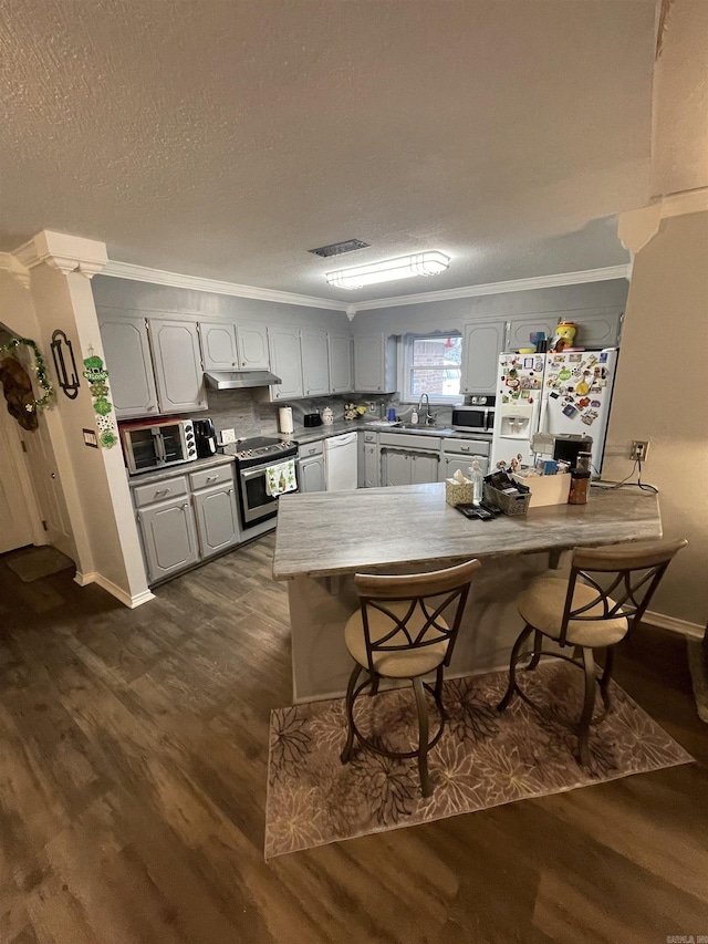 kitchen featuring a breakfast bar, stainless steel appliances, dark wood-type flooring, and a sink