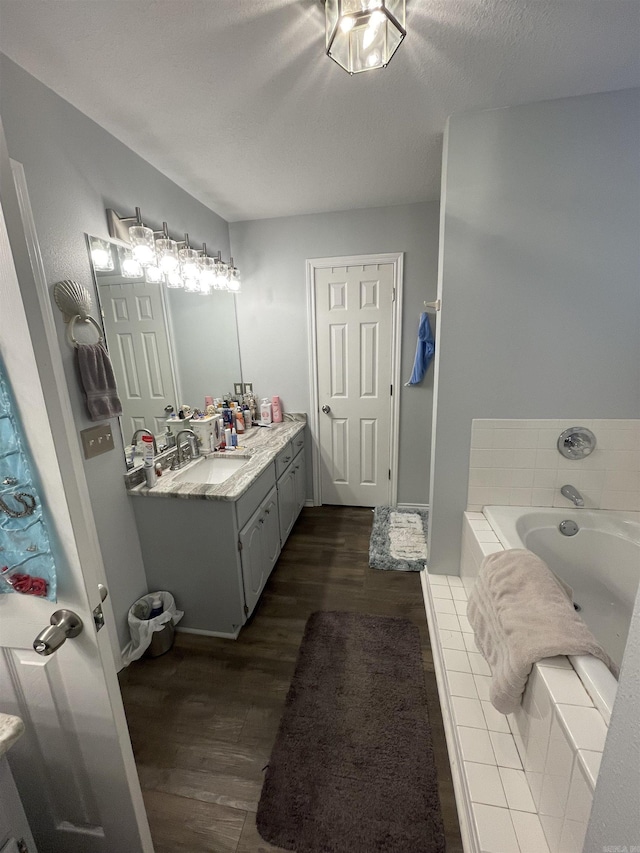 full bath featuring a bath, a textured ceiling, vanity, and wood finished floors