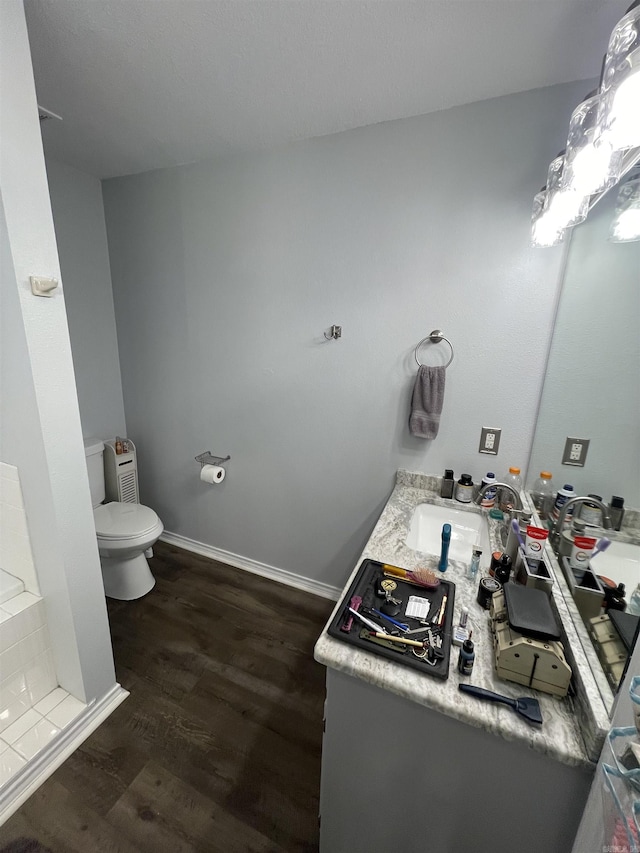 bathroom featuring vanity, toilet, wood finished floors, and baseboards