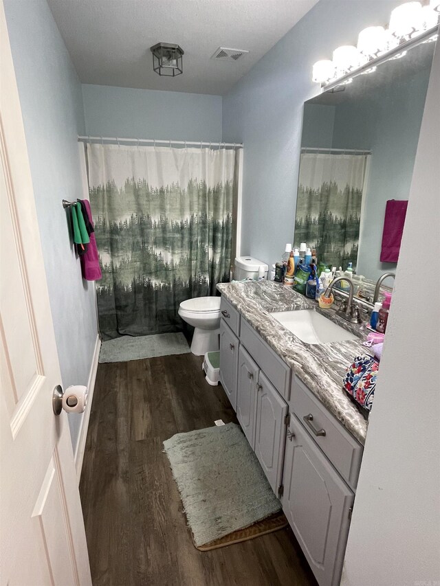 bathroom with visible vents, toilet, vanity, and wood finished floors