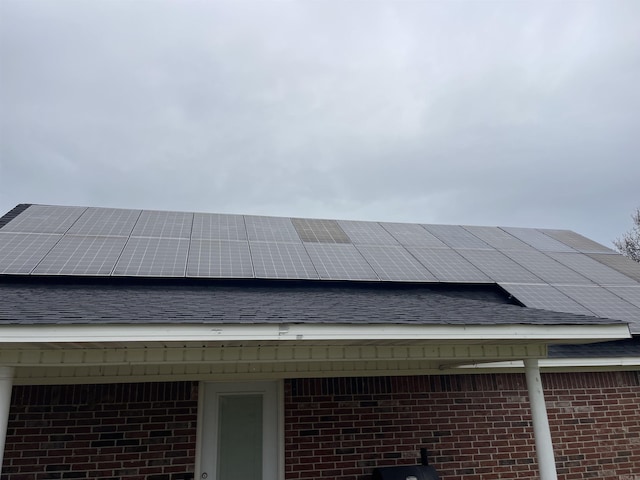 exterior details featuring brick siding and roof with shingles