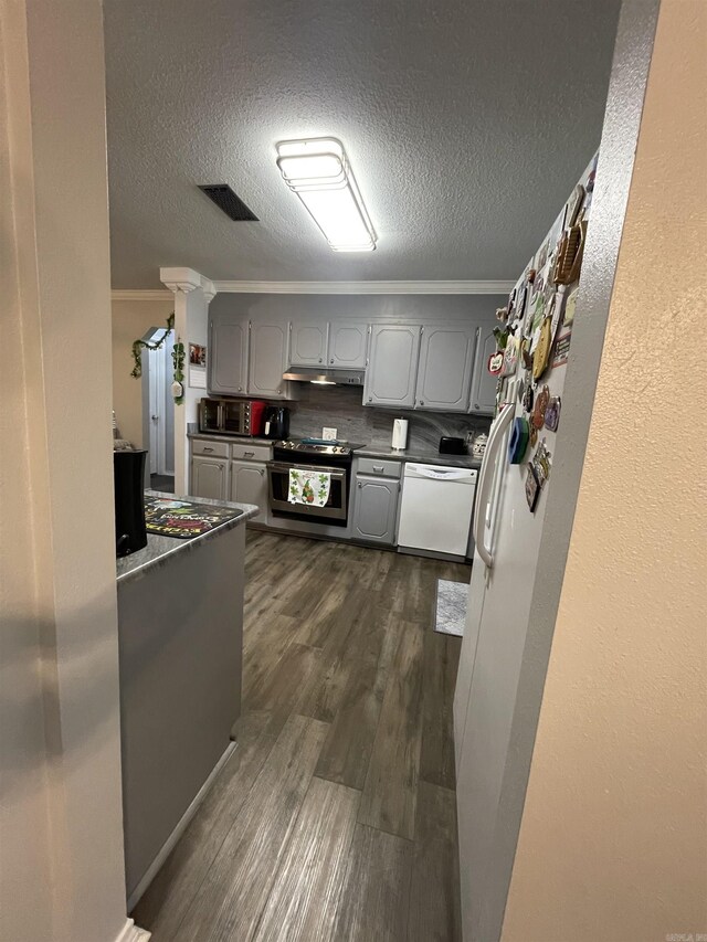 kitchen with visible vents, gray cabinetry, dark countertops, stainless steel appliances, and crown molding