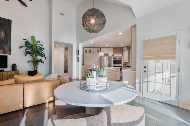 tiled dining space with visible vents, recessed lighting, and a high ceiling