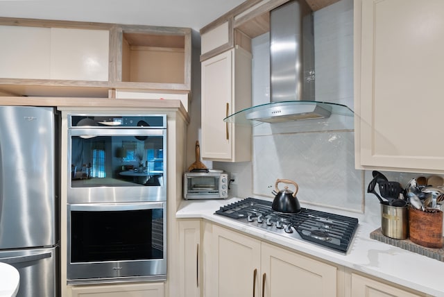 kitchen with a toaster, decorative backsplash, stainless steel appliances, white cabinetry, and wall chimney exhaust hood