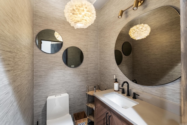 bathroom featuring toilet, vanity, and an inviting chandelier