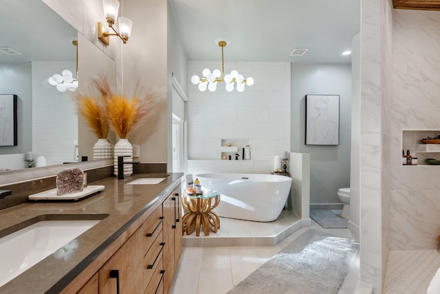 bathroom with visible vents, a chandelier, double vanity, a soaking tub, and a sink