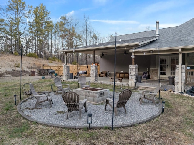 view of patio / terrace with a ceiling fan, french doors, fence, and an outdoor fire pit